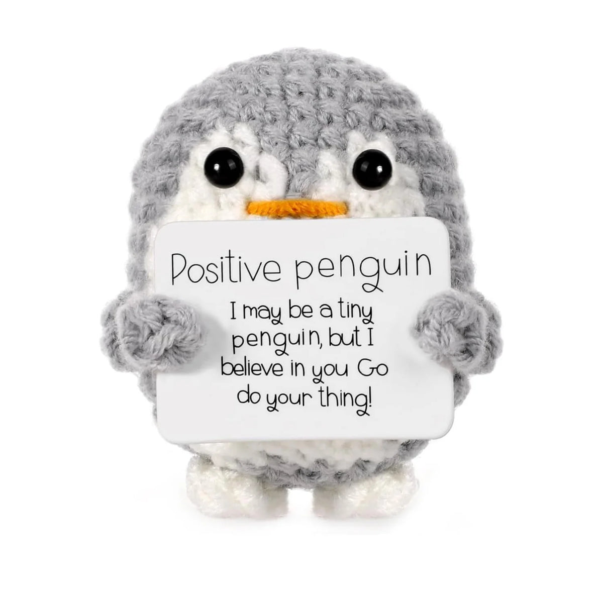 A handmade knitted grey penguin doll holding a white card with the text Positive penguin I may be a tiny penguin but I believ