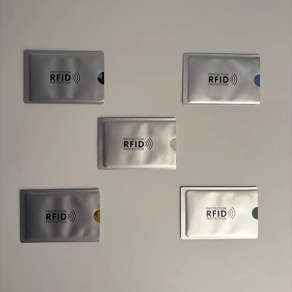 Five silver RFID protection card sleeves with geometric patterns arranged on a light gray background.