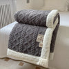 A gray double-layer fleece throw blanket folded on a white bed with white and gray accents.