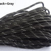 A bundle of black and gray 7-strand paracord rope is shown coiled on a white surface.