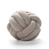 A round, light gray velvet throw pillow with a tightly knotted texture.
