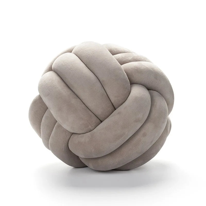 A round, light gray velvet throw pillow with a tightly knotted texture.
