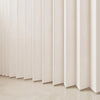 A close-up of a light beige, pleated fabric room divider curtain with vertical folds.