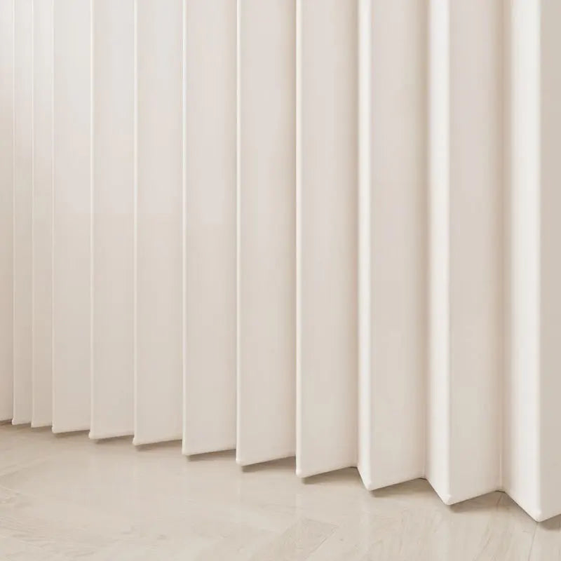 A close-up of a light beige, pleated fabric room divider curtain with vertical folds.