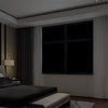 A modern bedroom interior featuring a large dark window with blackout privacy film.