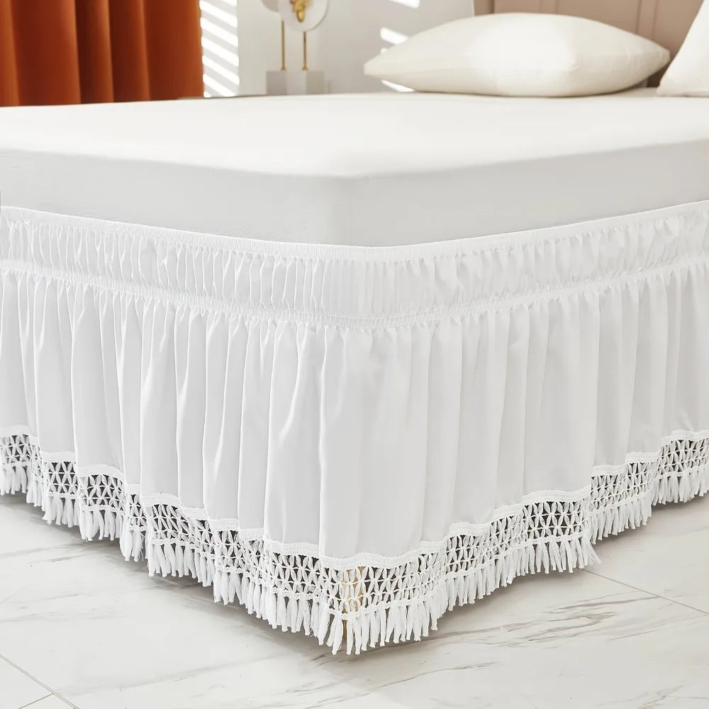 White elastic wrap-around ruffled bed skirt with lace trim on a white bed.