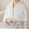 A person is wrapped in a white, fluffy throw blanket while holding a white mug. The blanket is described as ultra soft, light