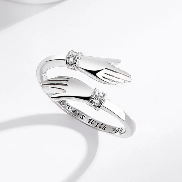 Nahaufnahme eines silbernen Umwerfungsrings mit Diamant-Handdesign und der Inschrift 'immer bei dir'.