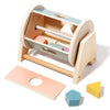 A wooden baby rattle bell with a soothing ring and various colored components is shown on a light wood background.