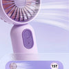 A close-up view of a light purple handheld fan with a grille and a power button, showing airflow lines.