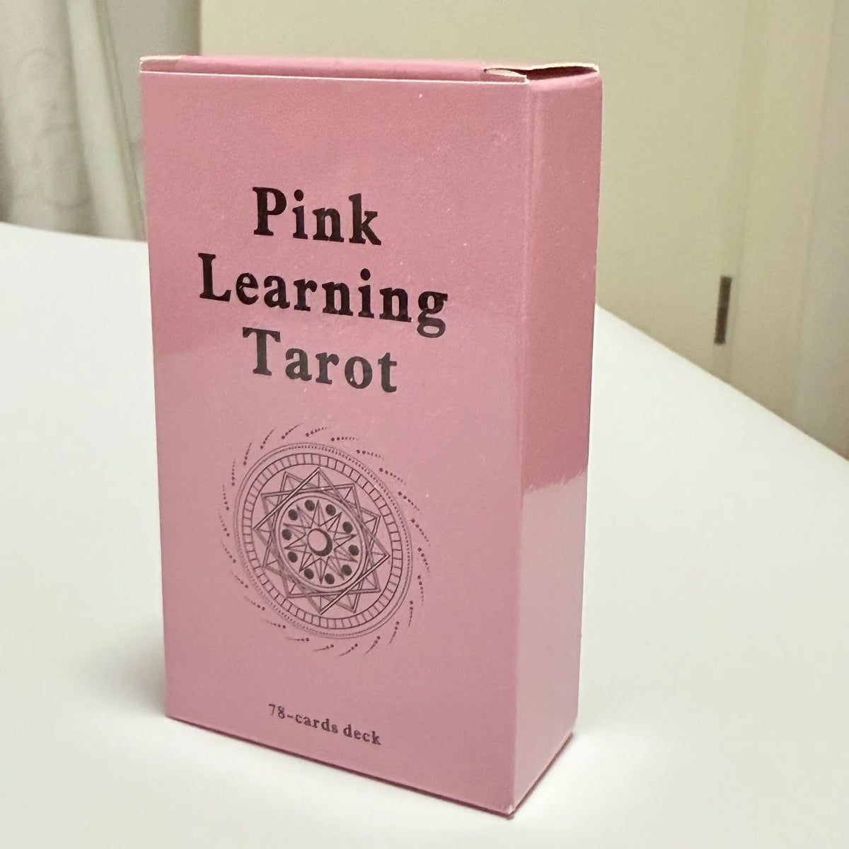 A pink box for the Pink Learning Tarot deck featuring a circular design.