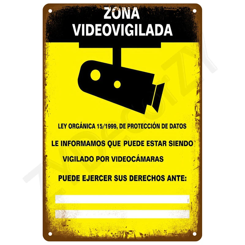 A yellow metal sign with black text and an illustration of a surveillance camera, warning that the area is video-monitored.