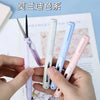 A hand holds several folding pen-shaped safety scissors in various colors, including purple, white, blue, and pink.