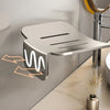 A silver aluminum wall-mounted soap dish with a drain is shown mounted on a wall.