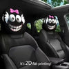 A pair of black car headrest covers featuring creepy, smiling monster faces with pink bows.