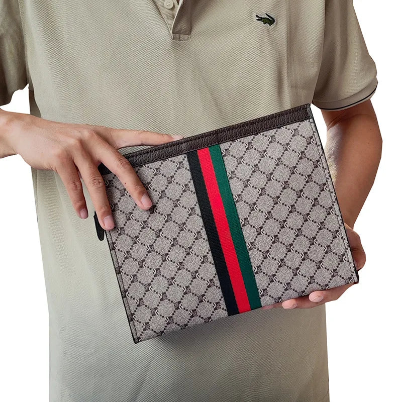 A hand holds a gray designer clutch bag featuring a checkered pattern and green and red stripes.