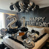 Silberne und schwarze Ballons, die 'Happy Birthday' bilden, hängen von der Decke