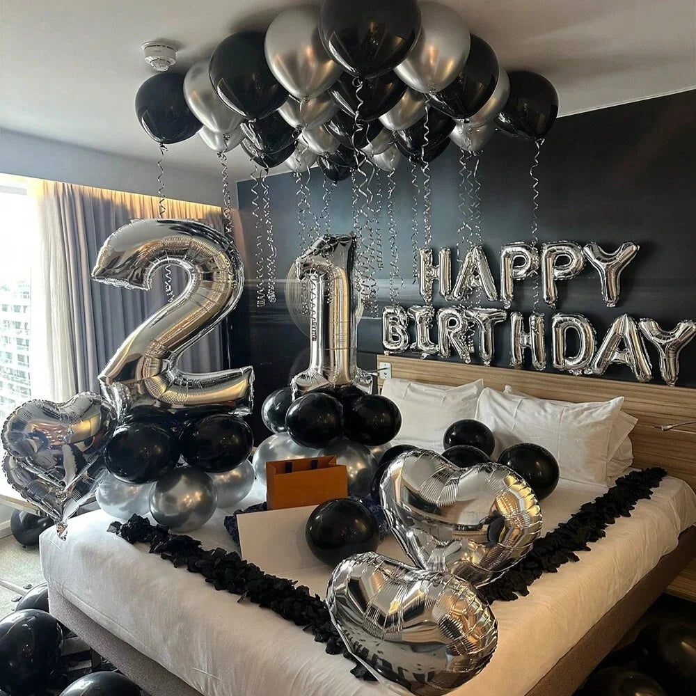 Silberne und schwarze Ballons, die 'Happy Birthday' bilden, hängen von der Decke