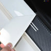 A hand is applying a white PU leather door sill protector sticker to the side of a white vehicle.