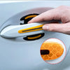 A hand is applying a carbon fiber reflective sticker protector to a car door handle.