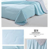 Light blue ice silk cooling blanket draped on a bed, showing its soft texture and folds.
