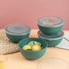 A set of teal airtight storage bowls and lids displayed on a light orange surface.