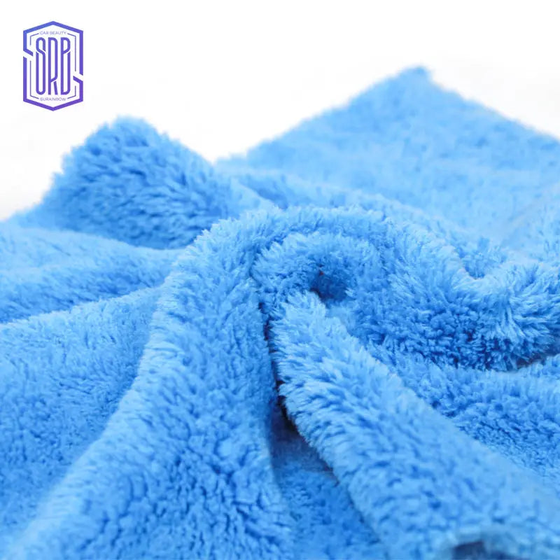 A close-up of a bright blue, fluffy microfiber cleaning cloth being folded or draped.
