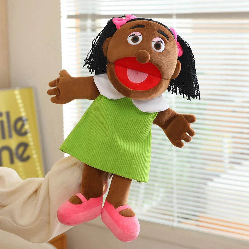 A soft plush full-body hand puppet of a girl with dark hair and pink accents wearing a green dress and light fabric.