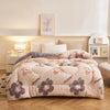 A beige plush throw blanket with floral patterns is displayed on a bed in a bright room.