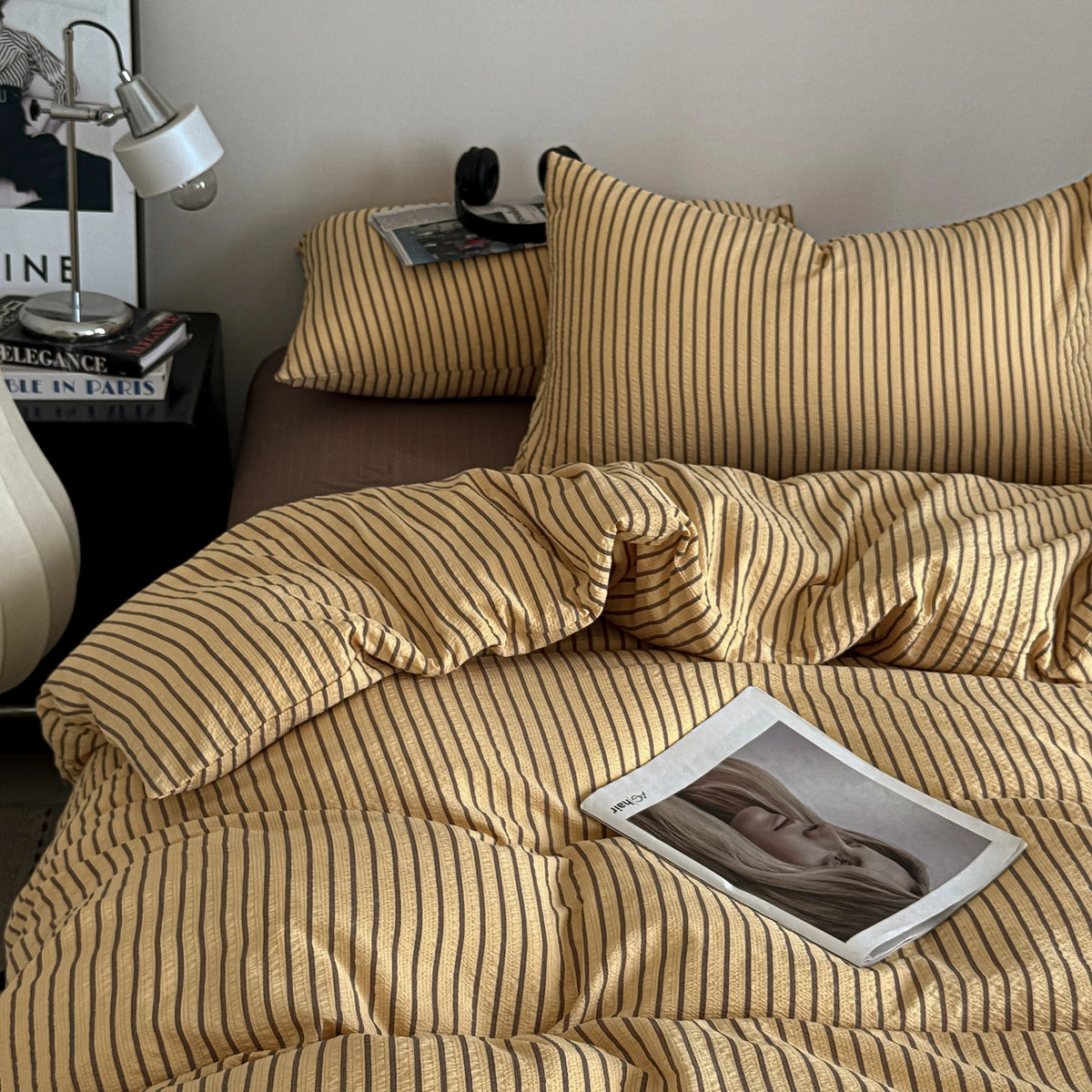 A close-up of a gold and beige striped duvet cover set with pillows on a bed.