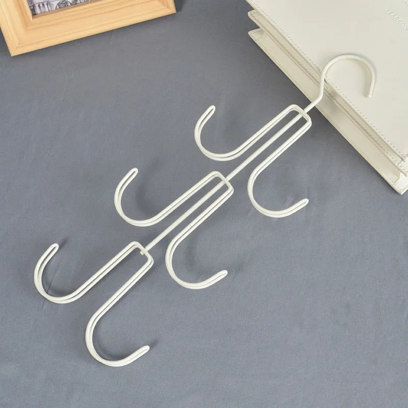 A white rotatable 3-layer hanging organizer for hats, bags, and scarves lying on a gray surface.