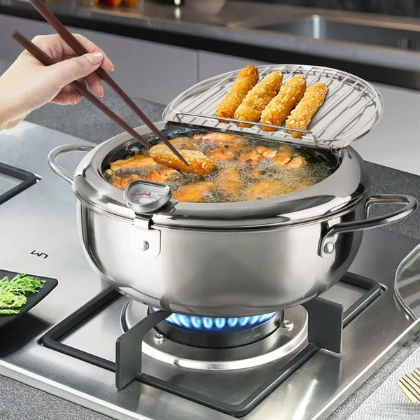 Una olla de freidora de acero inoxidable en una estufa con comida frita dorada y una canasta de alambre.