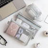 A transparent mesh storage bag organizer with a zipper holds various small items like cards, coins, and travel essentials.