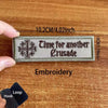 A rectangular embroidered patch with the text Time for another Crusade on a khaki fabric background.