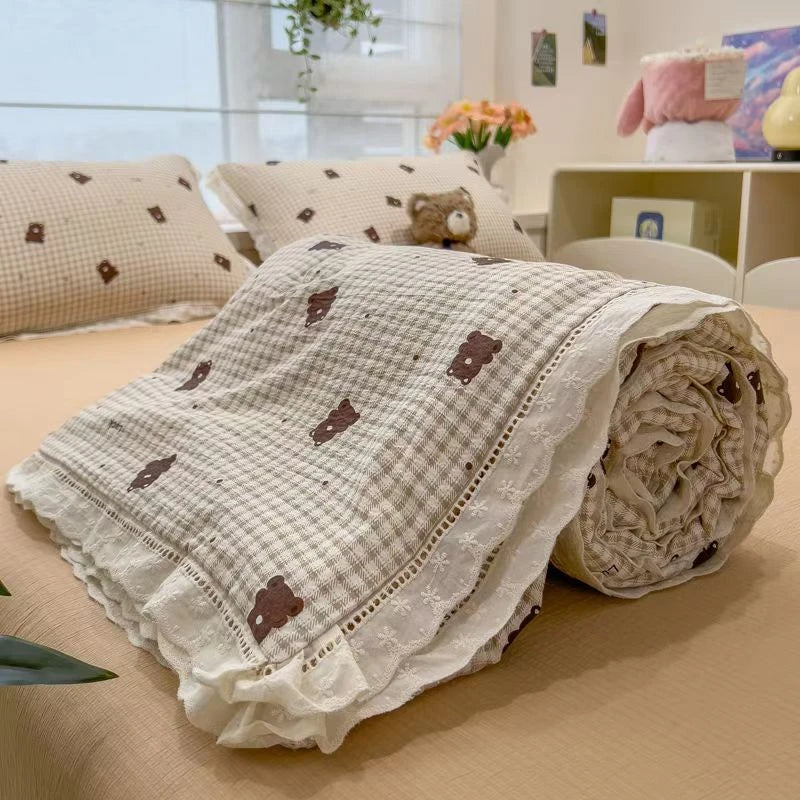 A rolled floral washed cotton gauze summer quilt with small brown embroidered shapes on a tan background.