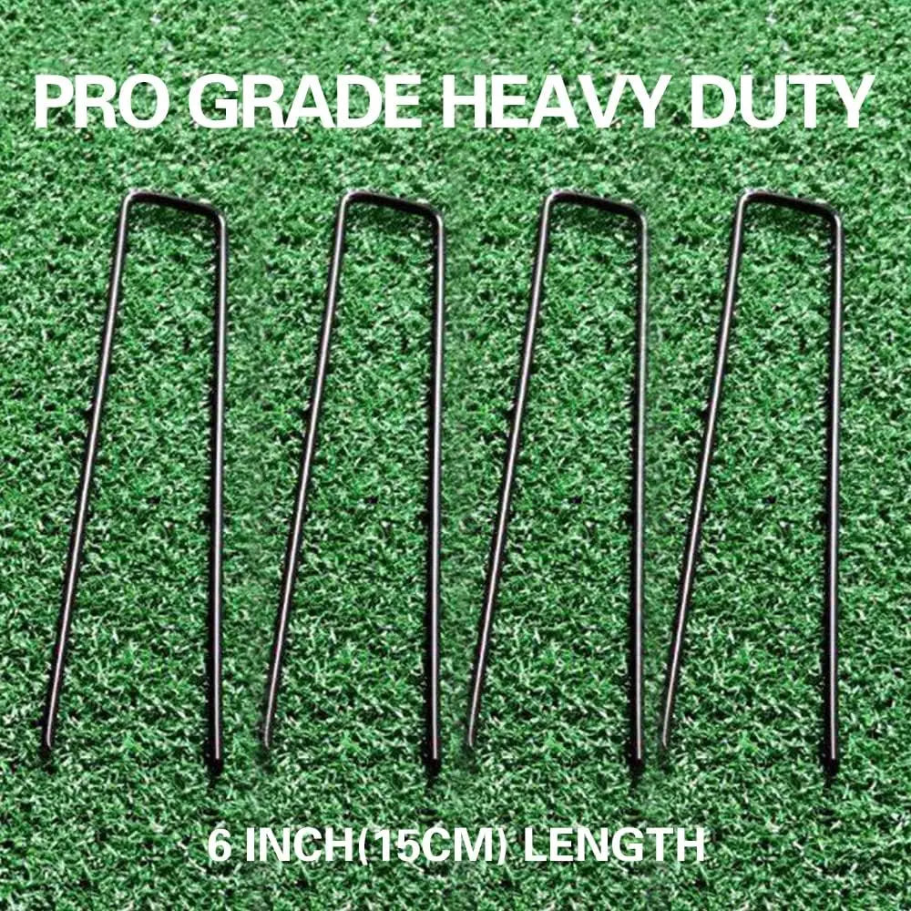 Six 6 inch galvanized U-shaped garden staples lying on green grass.