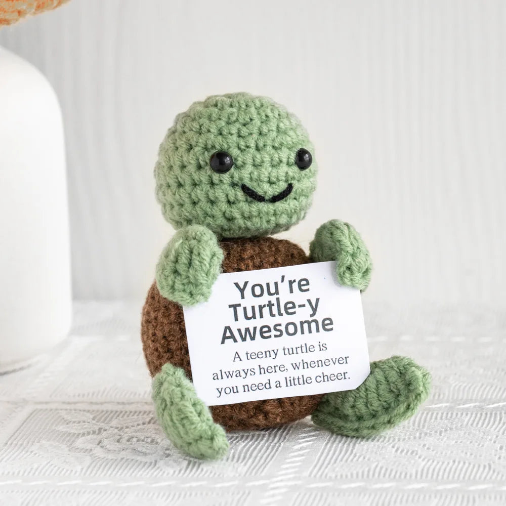 A handmade crochet turtle doll with a smiling face and brown body, used as funny emotional support decor.