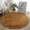 A round, golden brown shaggy rug placed on a light wood floor in a living room setting.
