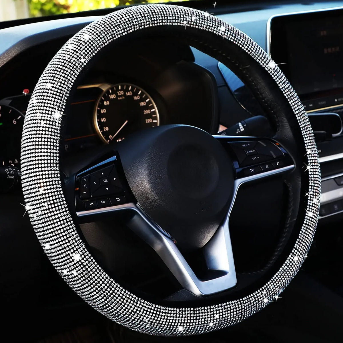 Gros plan d'un volant noir avec une housse en strass scintillants à l'intérieur d'une voiture.