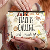 A hand holds an Italian souvenir travel makeup bag with a yellow and white pattern, featuring the text Italy is calling and I