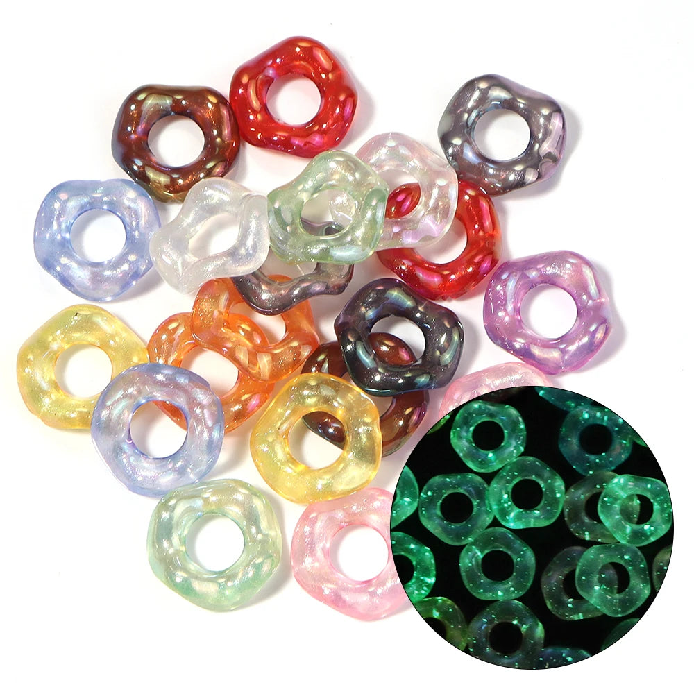 A collection of colorful acrylic spacer beads in various shades including red, green, purple, and clear, arranged on a white 