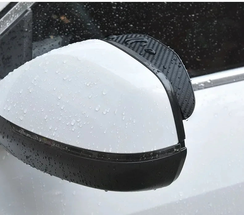 A close-up of a black carbon fiber car side mirror rain and sun visor installed on a vehicle.