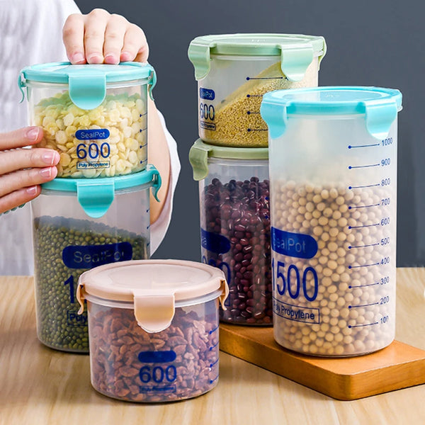 Una mano sostiene varios recipientes transparentes y herméticos para almacenar alimentos con balanzas y tapas, mostrando gran