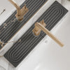 A brass faucet mat with a spiral design is placed on a white marble countertop.