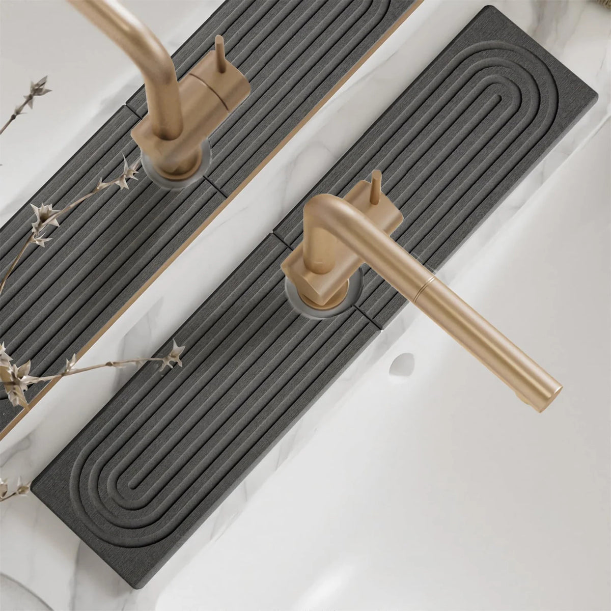 A brass faucet mat with a spiral design is placed on a white marble countertop.
