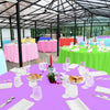 A vibrant purple round tablecloth is set with white plates, silverware, and glassware for an event.