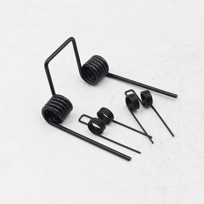 A collection of black double torsion springs with long wires and coiled ends.