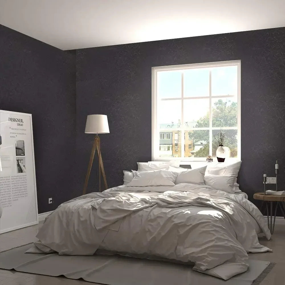 A bedroom featuring a large window and a bed with white linens against a dark gray wall.