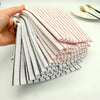 A hand holds a stack of striped lint-free kitchen dishcloths in white, red, and black stripes.