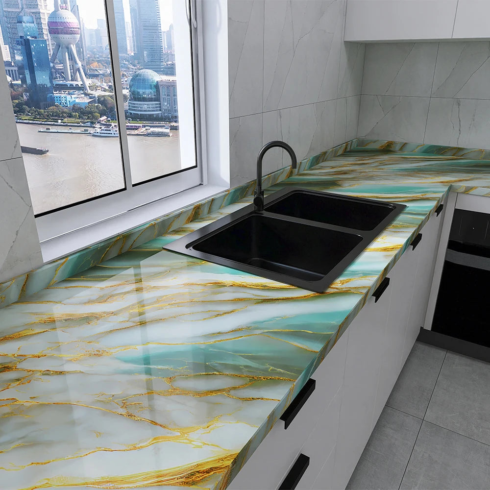 A kitchen countertop with a marble effect featuring teal and gold veining, housing a black sink.